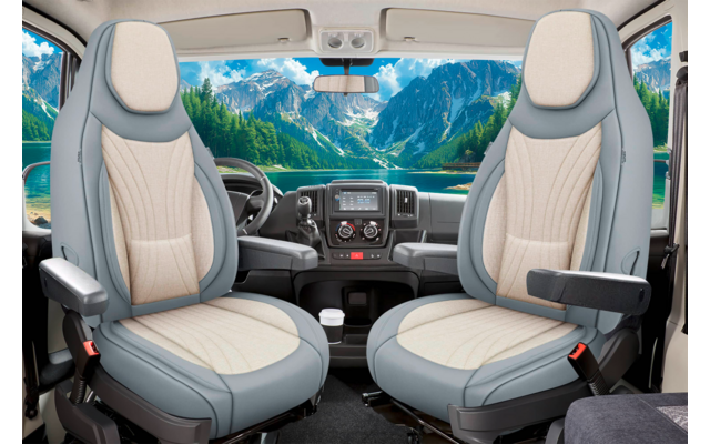 Zwei drehbare Vordersitze in einer Fahrerkabine mit Armlehnen und Kopfstützen, Lenkrad, Armaturenbrett mit Mittelkonsole und Becherhalter; durch die Windschutzscheibe Berge, See, Nadelbäume und blauer Himmel