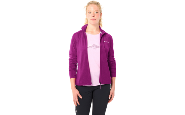 Stehende Person mit zusammengebundenen hellen Haaren, lila Reißverschlussjacke über rosa T‑Shirt mit Berggrafik, dunkle Hosen, Hände seitlich, weißer Hintergrund