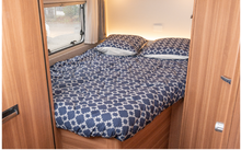Opgemaakt bed met blauw patroon dekbed in een camper