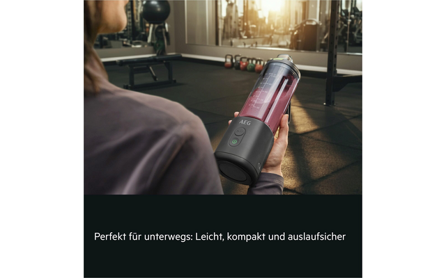 Personne vue de dos tient un mixeur portable à base grise et récipient transparent avec smoothie rouge; logo 'AEG' sur la base; en arrière-plan une salle de sport avec kettlebells, bancs et miroirs; en bas le texte: Perfekt für unterwegs: Leicht, kompakt und auslaufsicher
