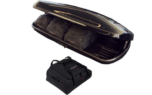 Offener glänzender schwarzer Dachkoffer mit drei schwarzen Reisetaschen im Inneren und einer schwarzen Tasche daneben auf weißem Hintergrund