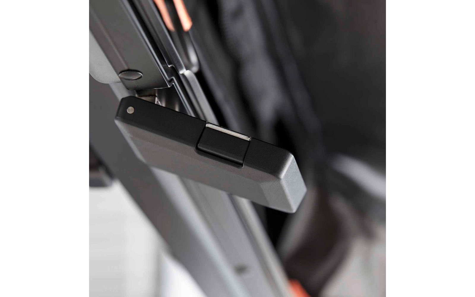 Nahaufnahme eines schwarzen Kunststoffverschlusses an einem Metallrahmen, im Hintergrund schwarzer Stoff