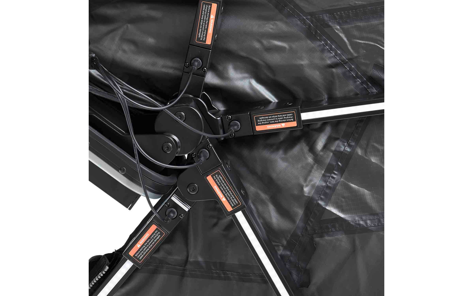 Schwarzer Stoff mit drei schwarzen Metallgelenken und silbernen Stangen, an den Gelenken orange Warnaufkleber und Kabel