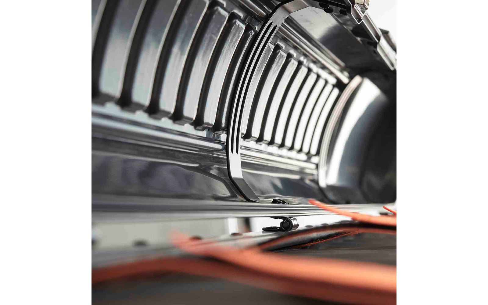 Innenraum eines gebogenen Metallgehäuses mit parallelen Lampenröhren und einer orangefarbenen Brille