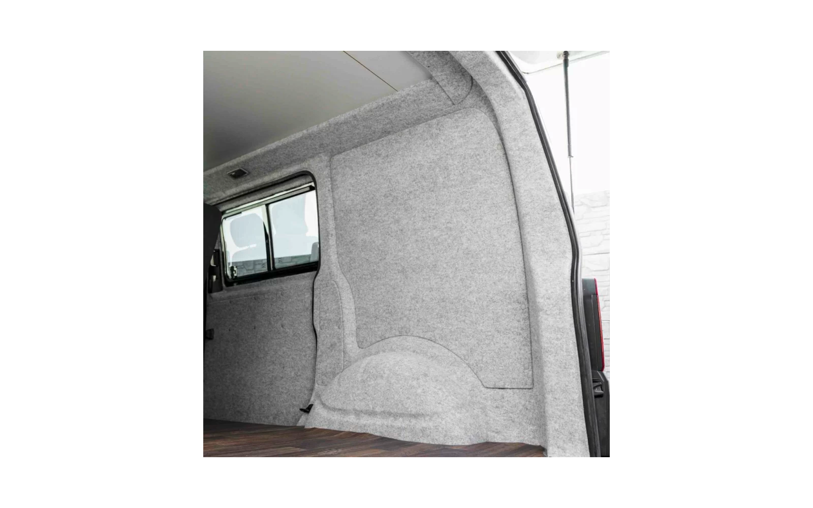 Innenraum eines Lieferwagens mit grauer Filzverkleidung, sichtbar abgedeckte Radkastenverkleidung, Holzboden und offene Seitentür