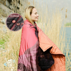 Frau mit rosa Jacke steht draußen, im Hintergrund Gras und Wasser