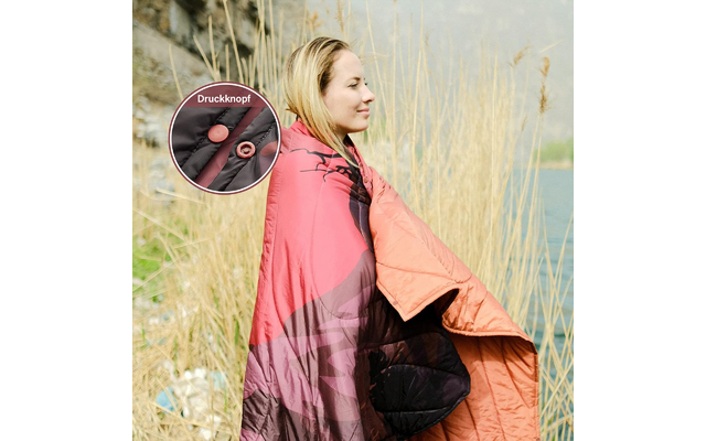Frau mit rosa Jacke steht draußen, im Hintergrund Gras und Wasser