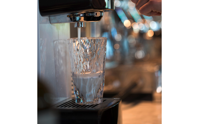Ein Glas unter einer Kaffeemaschine, das mit Wasser gefüllt wird