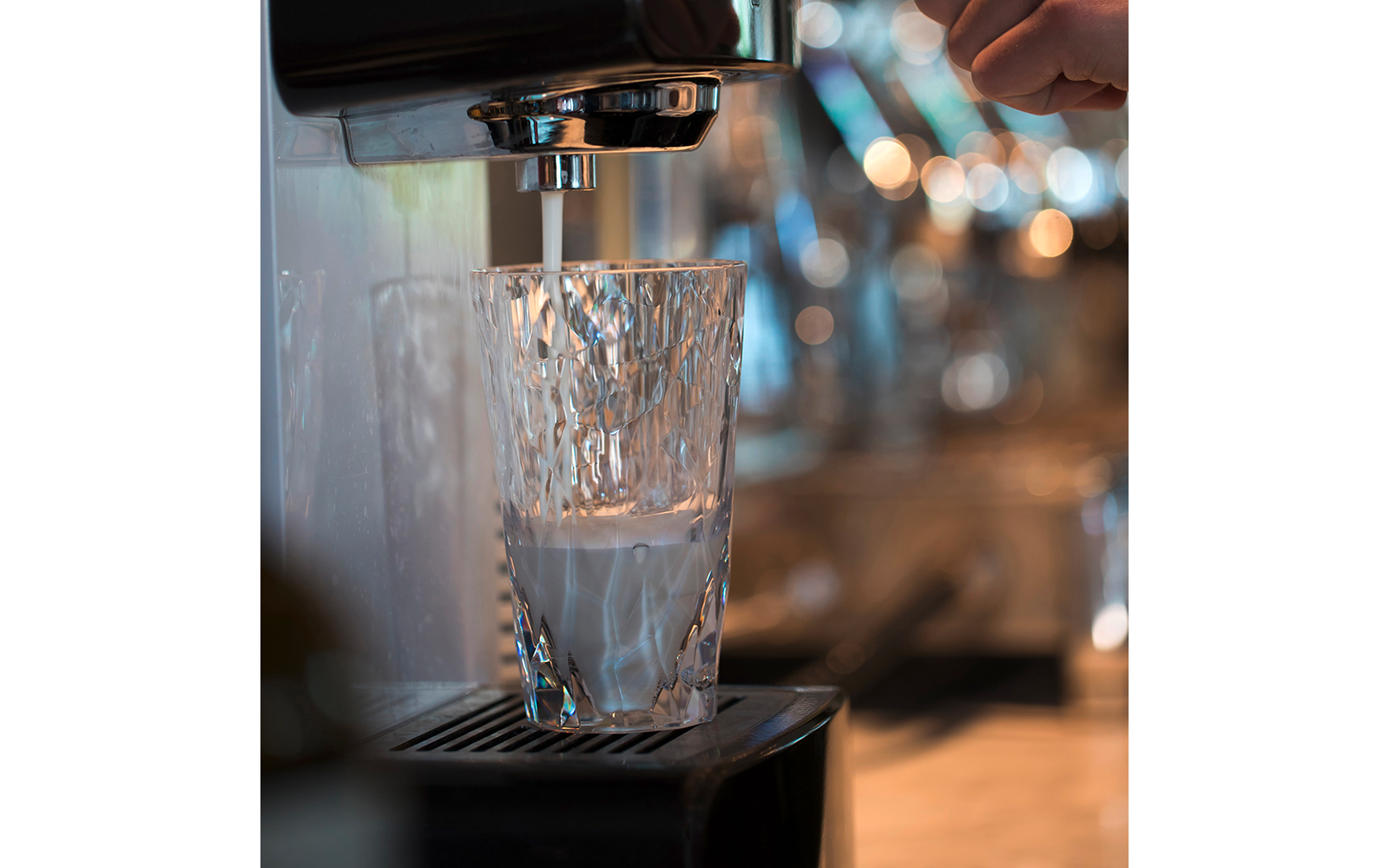 Ein Glas unter einer Kaffeemaschine, das mit Wasser gefüllt wird