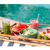 Tisch mit verschiedenen Getränken und Snacks vor einem Pool