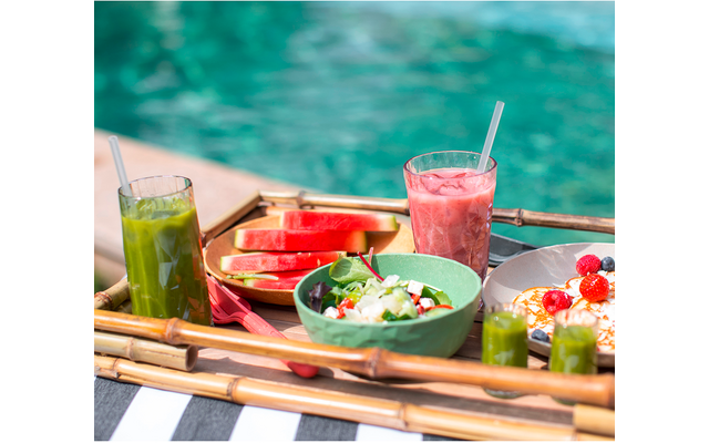 Tisch mit verschiedenen Getränken und Snacks vor einem Pool