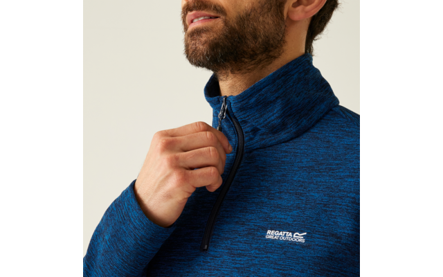 Ein Mann zieht den Reißverschluss seines blauen Fleece-Pullovers hoch