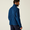 Mann mit dunklem Haar von hinten, trägt eine blaue Jacke und schwarze Hose