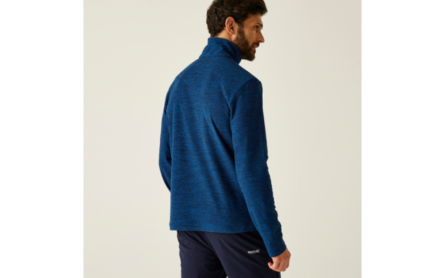 Mann mit dunklem Haar von hinten, trägt eine blaue Jacke und schwarze Hose