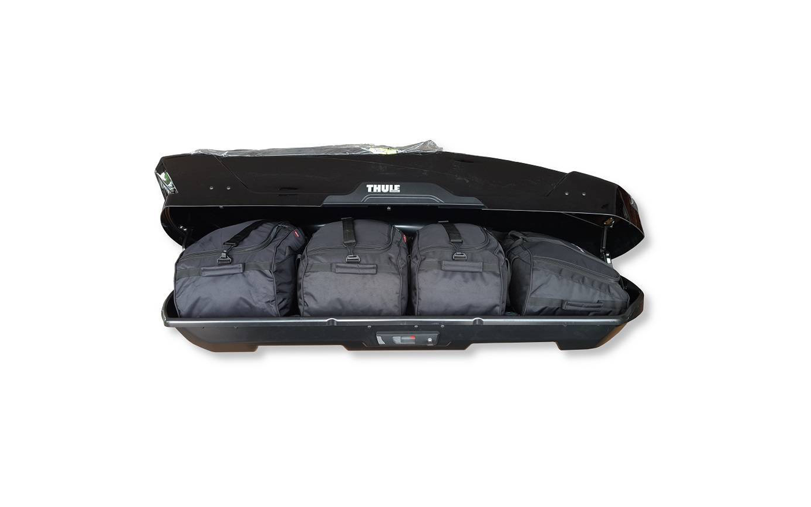 Coffre de toit noir ouvert avec le logo «Thule» visible et quatre sacs de voyage noirs à l'intérieur