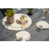 Table en bois foncé avec des sets ronds en macramé crème, deux flûtes contenant une boisson dorée, une bouteille, un bol blanc d'olives et un petit pot avec une plante verte
