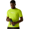 Man in neongroen T-shirt met bergmotiv, houdt een blauwe drinkfles vast en kijkt omlaag tegen een neutrale achtergrond