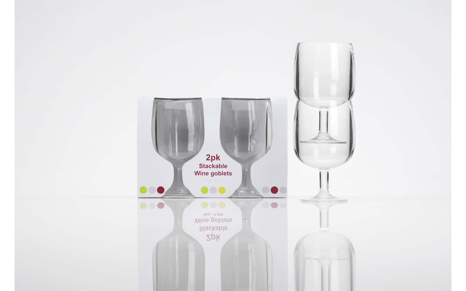 Zwei transparente Weingläser, eines auf dem anderen gestapelt rechts; links eine Verpackung mit Abbildungen der Gläser und dem Text 2pk Stackable Wine goblets, weiße Oberfläche mit Spiegelung