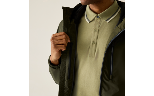 Oberkörper einer Person in olivgrünem Poloshirt mit gestreiftem Kragen und teilweise geöffneter dunkelgrüner Jacke, Hand hält den Jackenrand