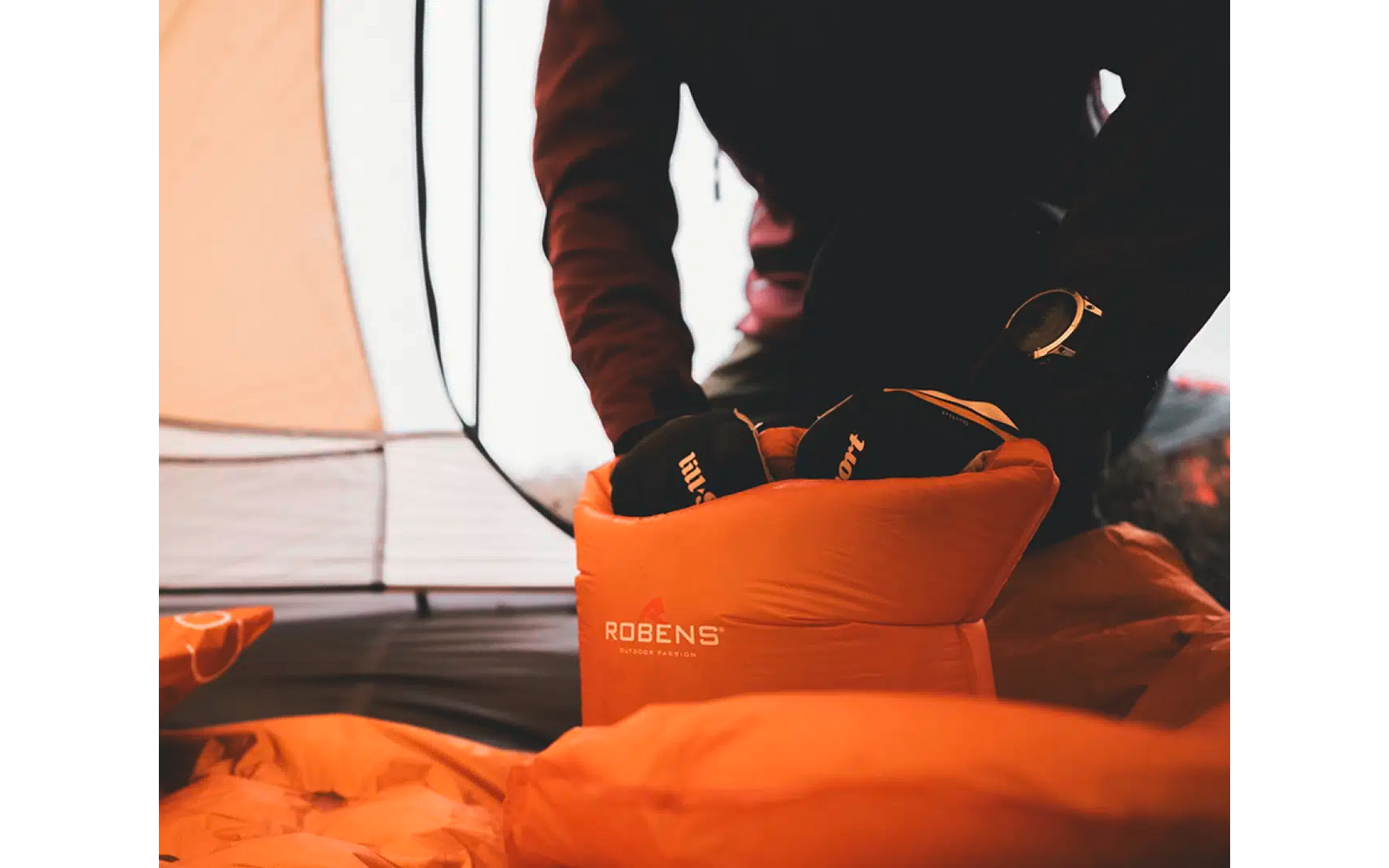 Persoon opent een oranje rugzak in een tent