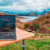 Ordinateur portable sur une table avec vue sur un paysage avec lacs, montagnes et ciel nuageux
