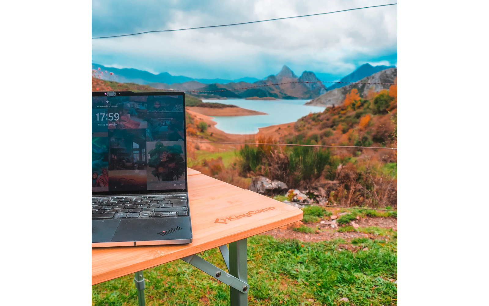 Ordinateur portable sur une table avec vue sur un paysage avec lacs, montagnes et ciel nuageux
