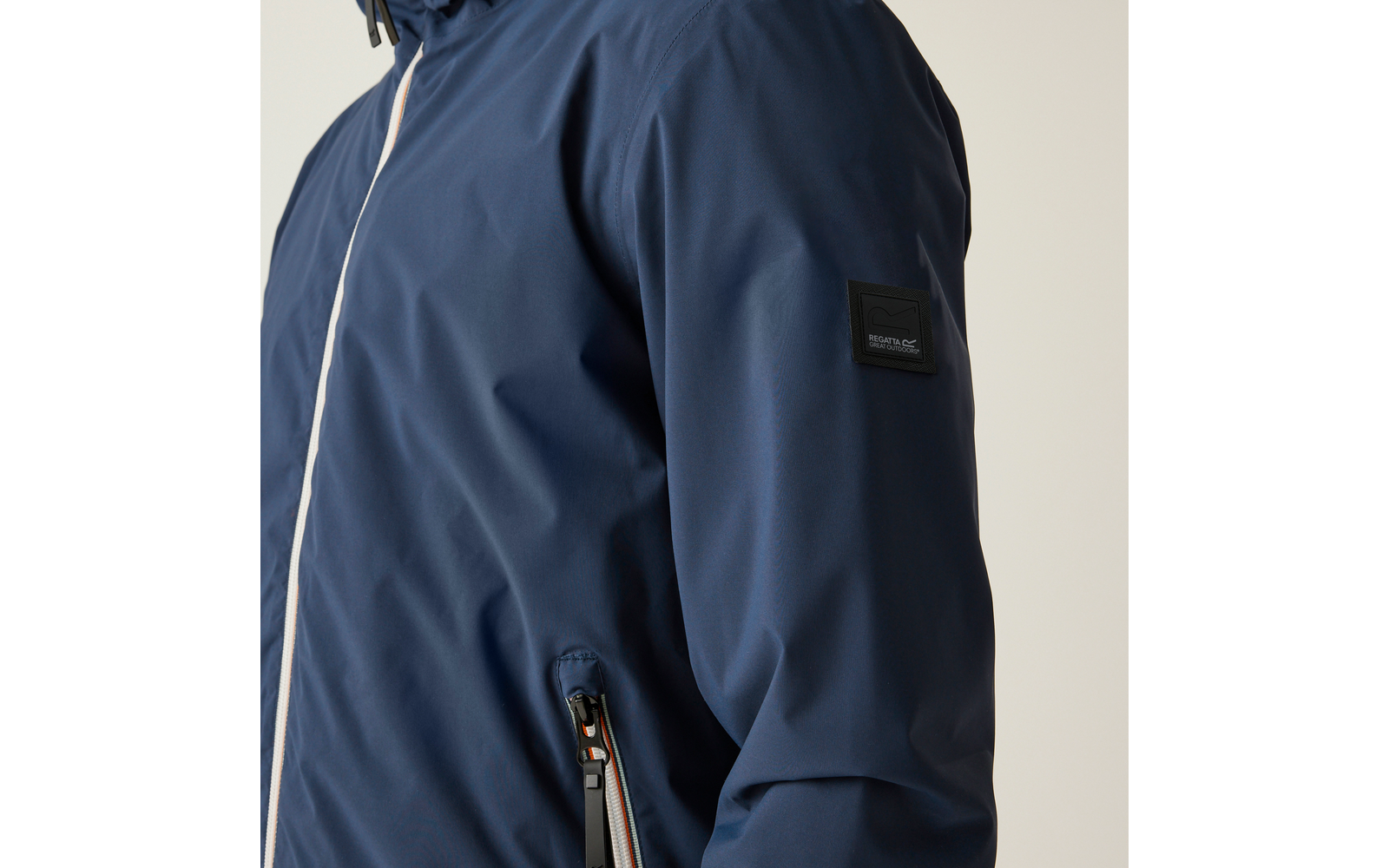 Seitliche Ansicht eines Oberkörpers in dunkelblauer Jacke mit weißer Reißverschlussleiste, Reißverschlusstasche mit Kontrastbesatz und kleinem Ärmelpatch