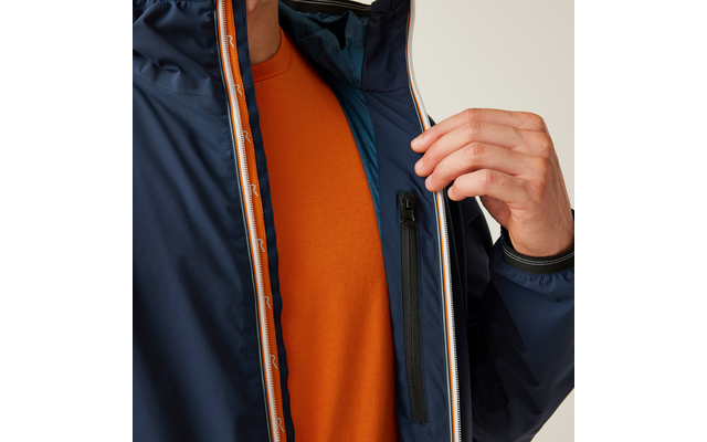 Oberkörper einer Person mit dunkelblauer, halb geöffneter Jacke; oranges T‑Shirt sichtbar; rechte Hand hält die Jacke geöffnet; Innentasche mit Reißverschluss sichtbar