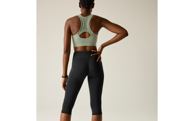 Person from behind, light green sports bra, black capri leggings, right hand on lower back, braided hair tied up