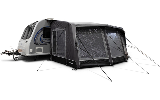 Wohnwagen mit angebautem dunkelgrauem aufblasbaren Vorzelt mit transparenten Fenstern, Abspannleinen und Anhängerkupplung sichtbar