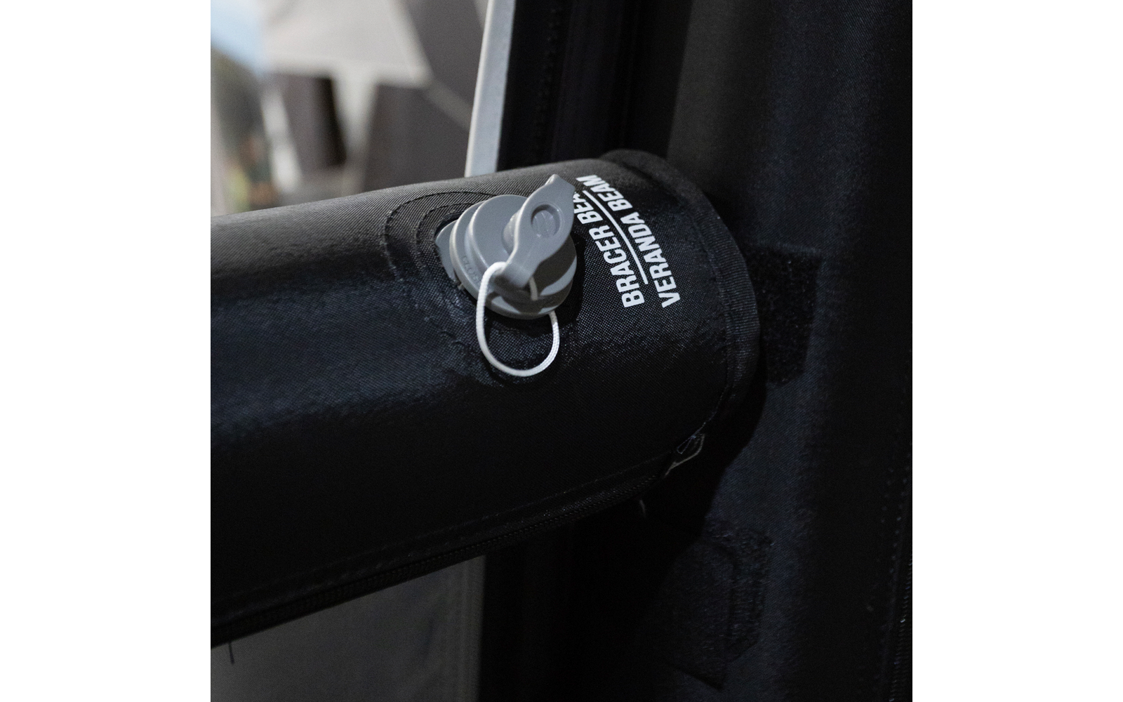 Nahaufnahme eines schwarzen, gepolsterten Rohrs mit grauem Kunststoffverschluss mit Ring und teilweise sichtbarer weißer Schrift