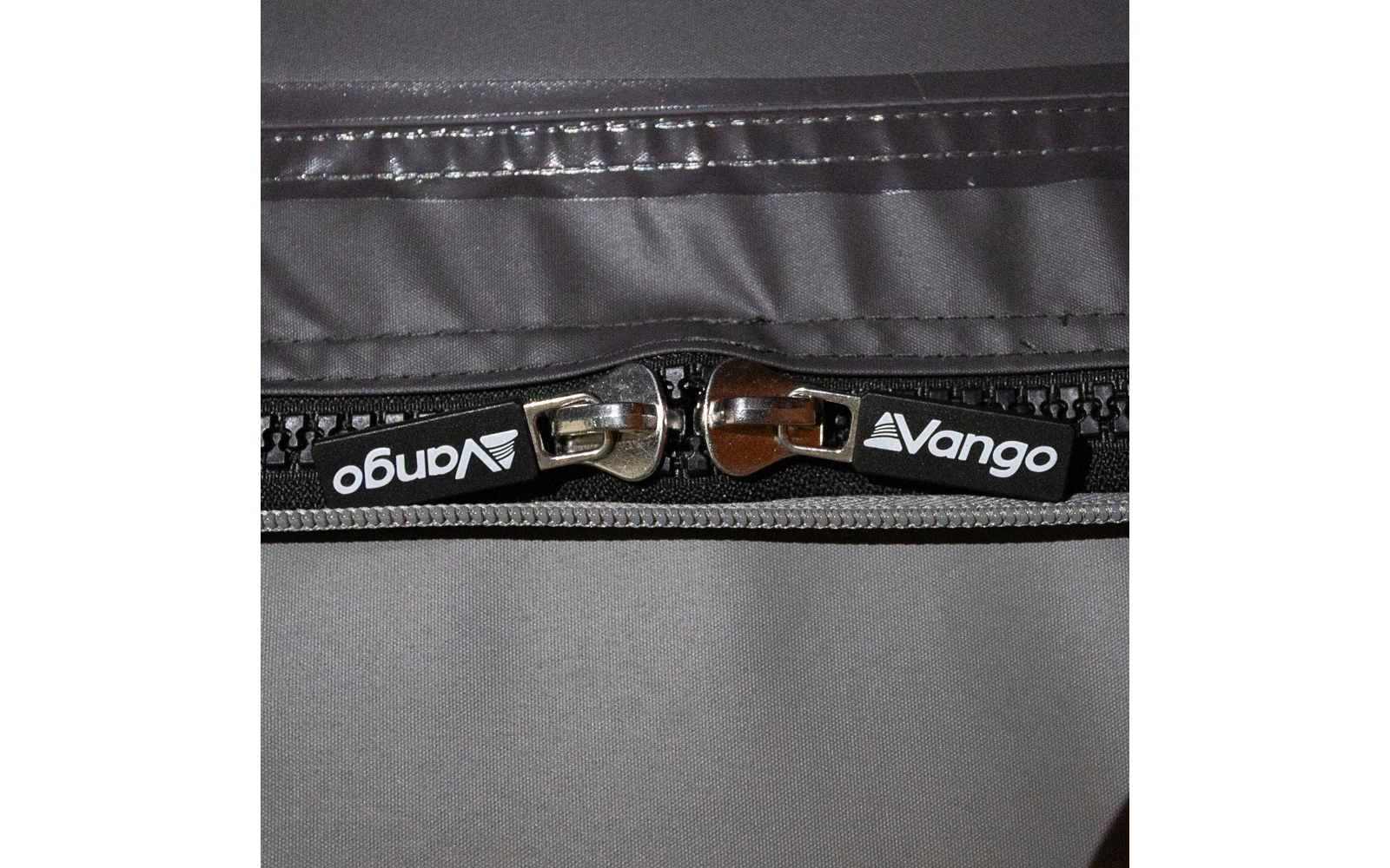 Nahaufnahme von zwei Reißverschlussschiebern mit Vango-Logo auf grauem Stoff