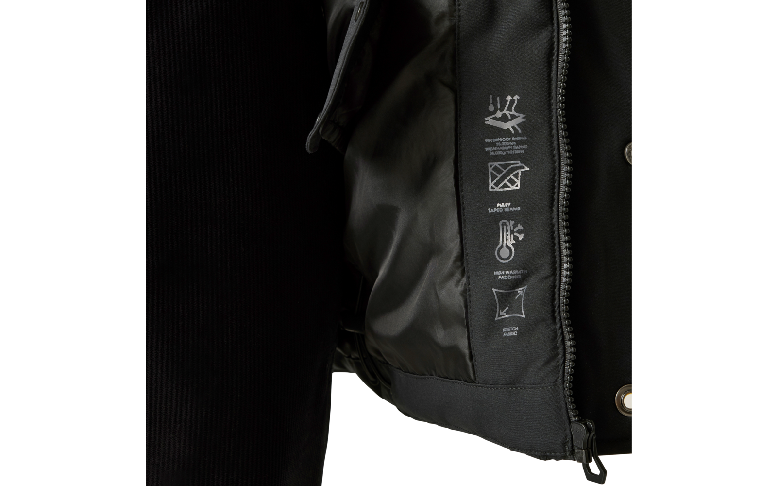 Nahaufnahme eines geöffneten schwarzen Jackets mit Innenfutter, Reißverschluss, Druckknopf, aufgedruckten Pflegesymbolen und einem Teil eines schwarzen, gerippten Ärmels