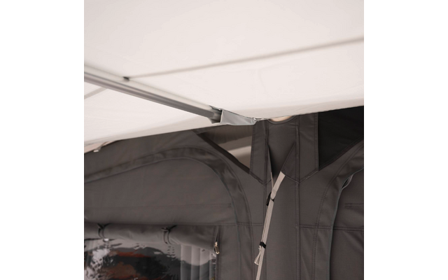 Nahaufnahme von grauen Stoffpanelen mit durchsichtigem Plastikfenster, Metallstange und Befestigungsriemen unter weißer Decke