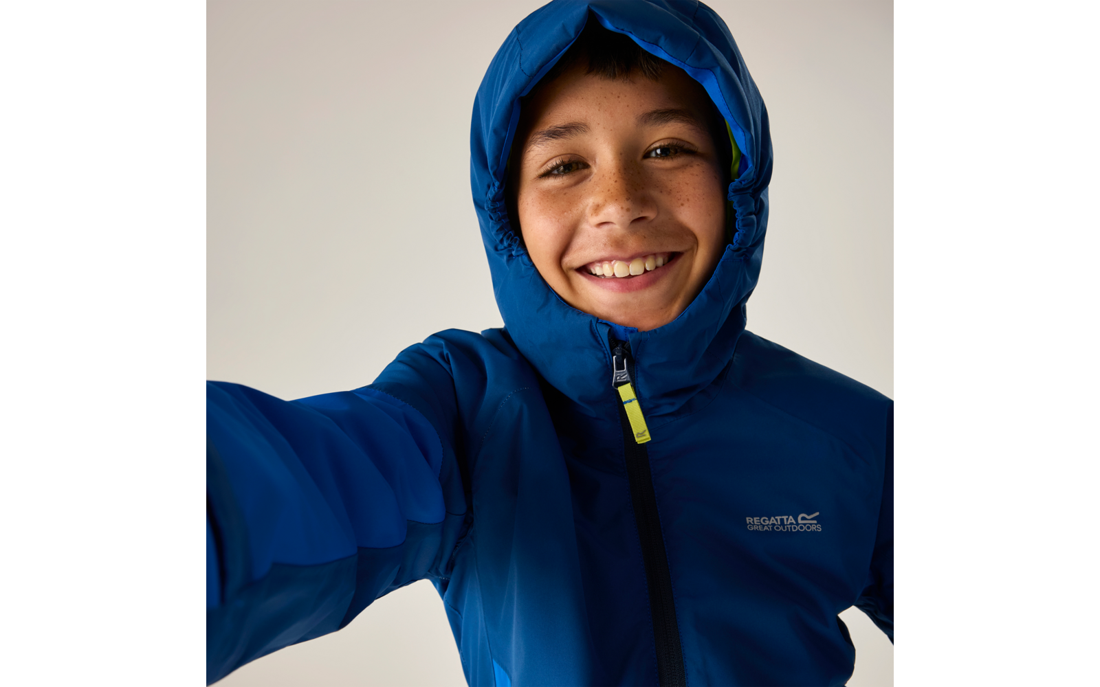 Person in blauer Kapuzenjacke, lächelnd, schaut in die Kamera