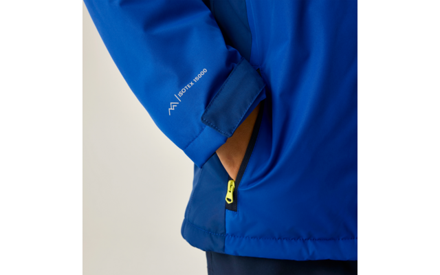 Blauer Jackenärmel mit Hand in seitlicher Reißverschlusstasche, gelber Reißverschluss-Anhänger, Aufdruck 'ISOTEX 10000' auf dem Ärmel, heller Hintergrund