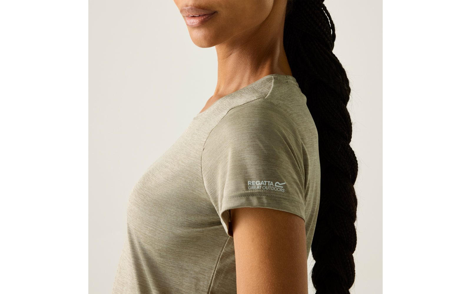 Bovenlichaam van een persoon van schouders tot kin, donker gevlochten haar, lichtgroen T-shirt met korte mouwen en het 'Regatta Great Outdoors'-logo op de mouw