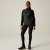 Persona in piedi, rivolta in avanti, indossa giacca nera trapuntata con cerniera, leggings neri e scarpe sportive nere, sfondo chiaro uniforme