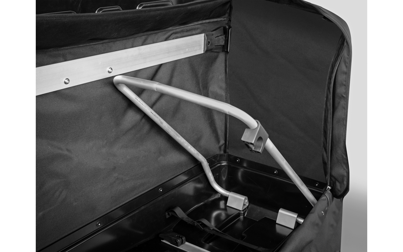 Offene schwarze Stofftasche mit sichtbarem silbernem Metallgestänge und grauen Kunststoffverbindern auf schwarzem Kunststoffboden