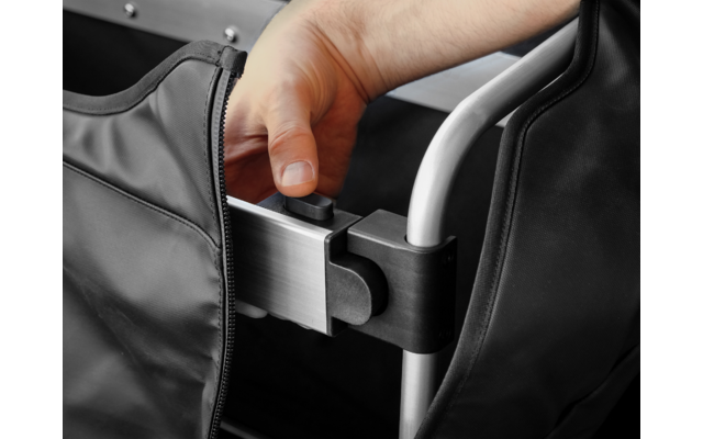 Hand greift schwarzen runden Knopf an einem silbernen Metallrohr; schwarzer Stoff mit Reißverschluss sichtbar