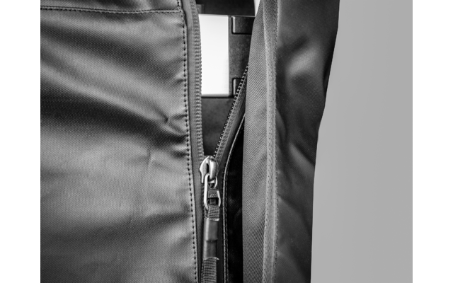 Nahaufnahme eines teilweise geöffneten Reißverschlusses an dunklem Stoff mit sichtbarem Zipper und Nähten