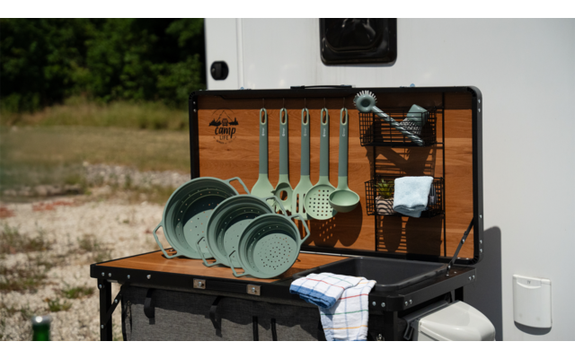 Campinggeschirr und Besteck vor einem Wohnmobil auf einem Klapptisch