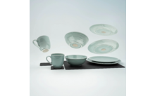 Meerdere beschilderde keramische kopjes en borden op een zwart oppervlak