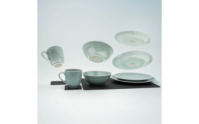 Meerdere beschilderde keramische kopjes en borden op een zwart oppervlak