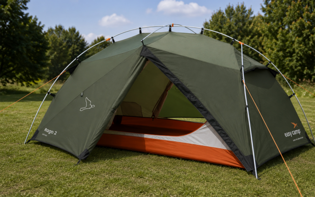 Groen koepeltent met open ingang waarin een oranje-witte slaapmat ligt, op gras voor bomen onder een blauwe hemel met enkele wolken