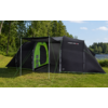 Zwarte tent met open ingang en groen binnenzeil, opgezet op gras, op de achtergrond bomen, een meer en een blauwe lucht met wolken