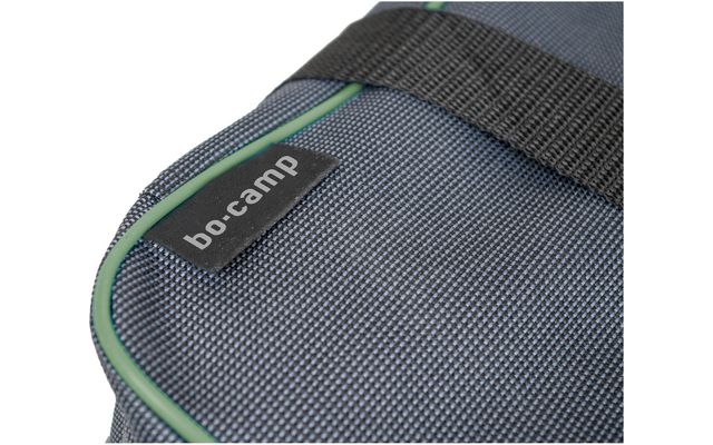 Gros plan d'un sac en tissu tissé gris foncé avec passepoil vert, sangle noire et étiquette noire avec texte blanc 'bo-camp'