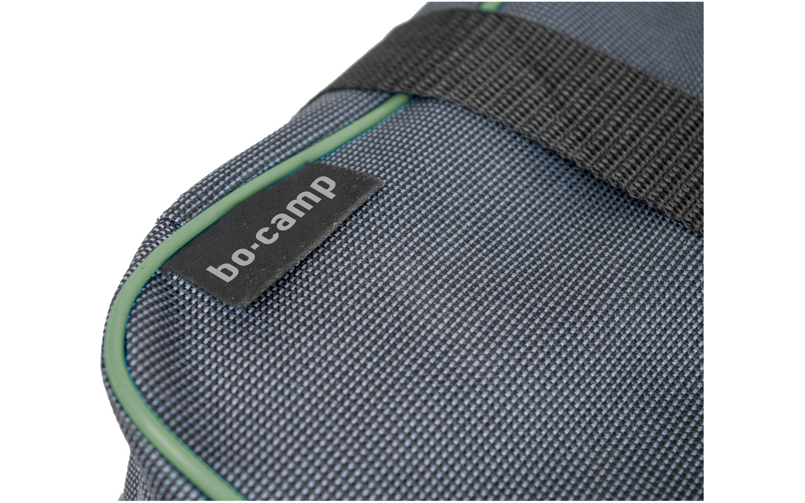 Gros plan d'un sac en tissu tissé gris foncé avec passepoil vert, sangle noire et étiquette noire avec texte blanc 'bo-camp'