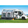 Motorhome with attached awning on a grassy field under a clear sky