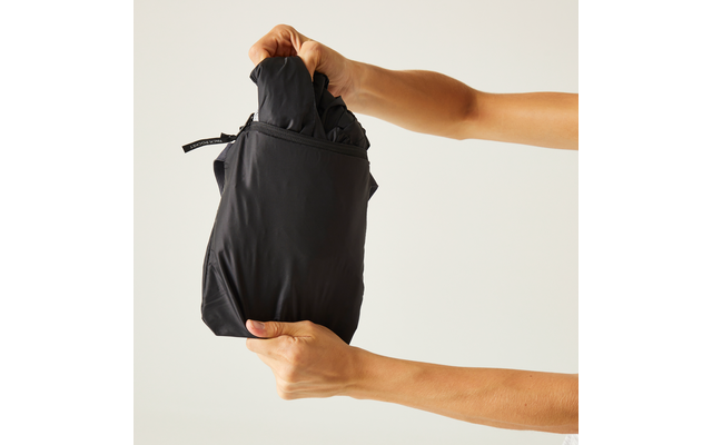 Due mani tengono un indumento nero piegato in una piccola sacca su uno sfondo chiaro